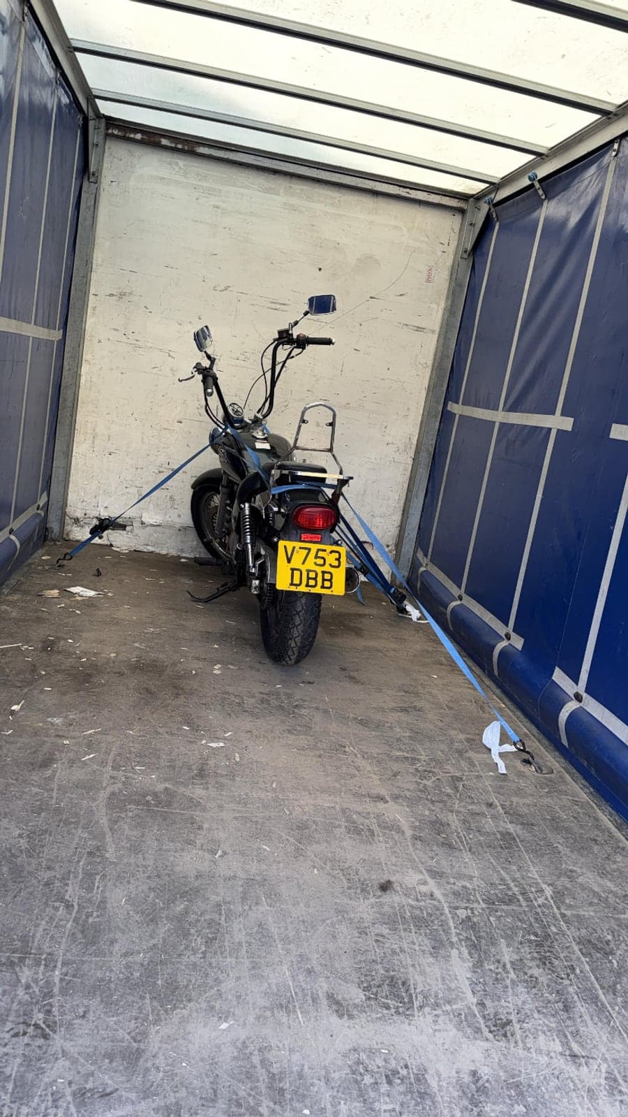 Motorcycle secured and strapped down for transport inside a Raymond Logistics van